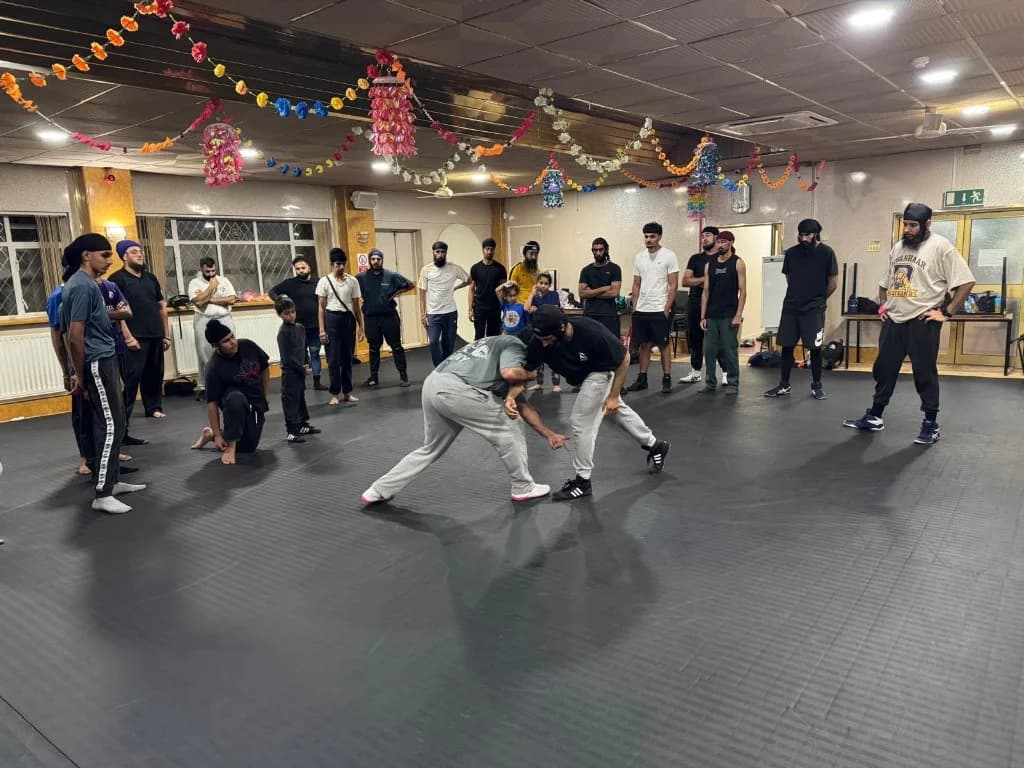 Two wrestlers practising a standing technique as the class watches